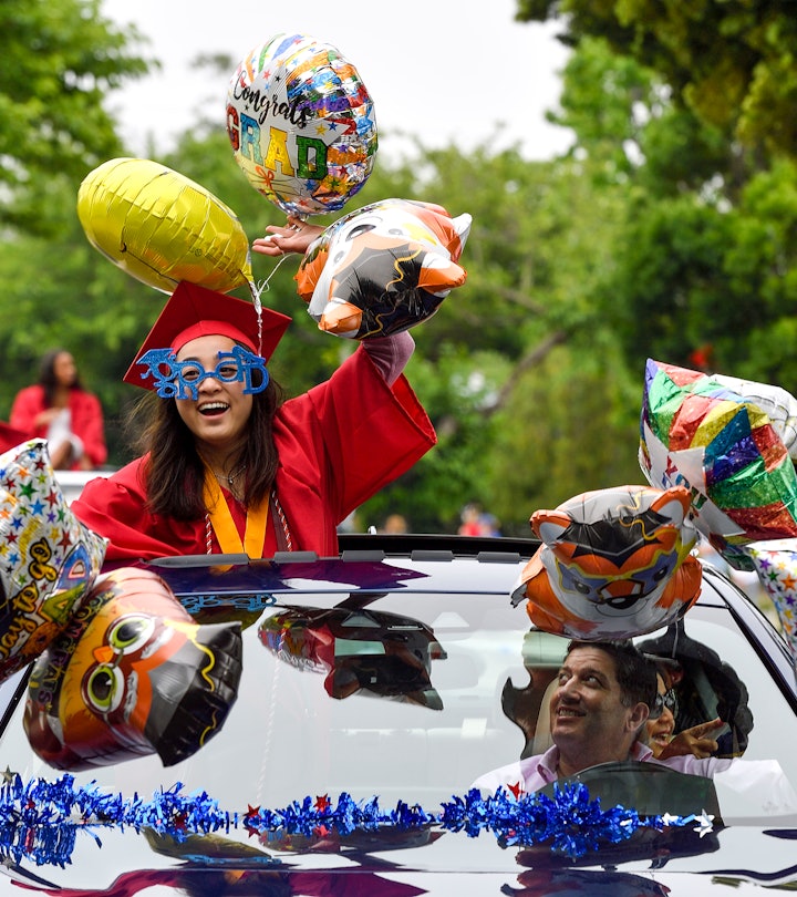 Los Alamitos High School graduate in a car with graduation-themed decorations