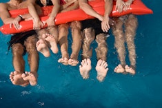 A group of boys in a pool holding on to an inflatable raft