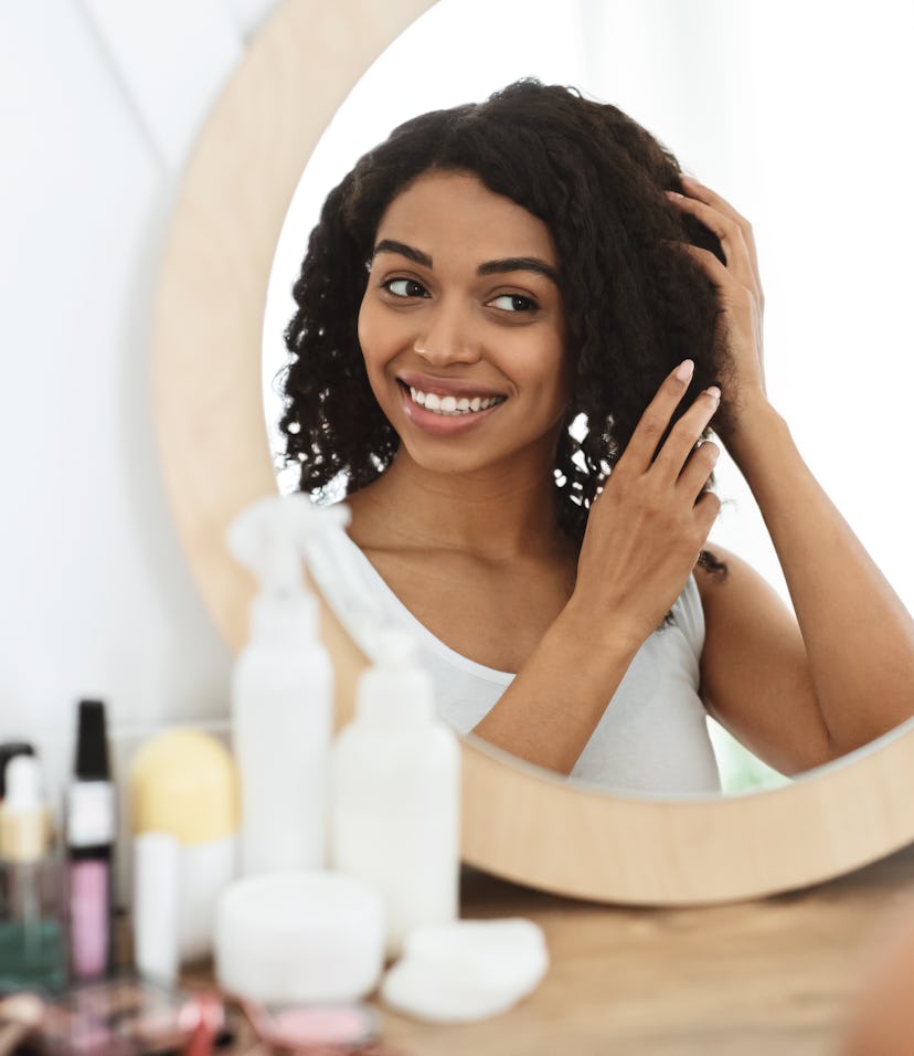 woman smiling in the mirror touching her hair