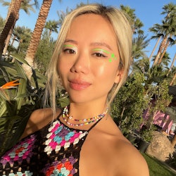 A blonde woman wearing a colorful crochet top with palms in her background