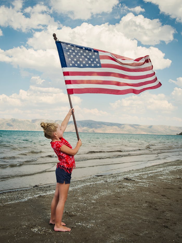 Last minute Memorial Day travel ideas; girl holding flag on beach