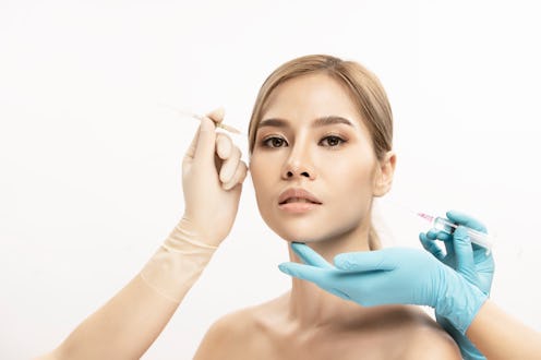 woman with cheek filler needle and glove hands
