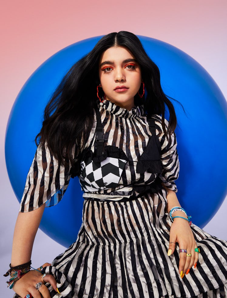 Actress Iman Vellani wearing a black and white outfit with bright orange makeup