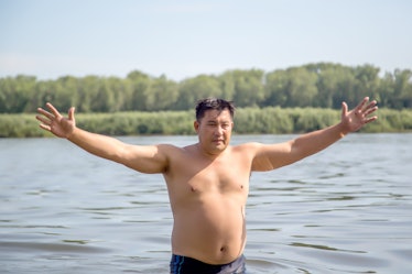 A fat man on the beach in the water.