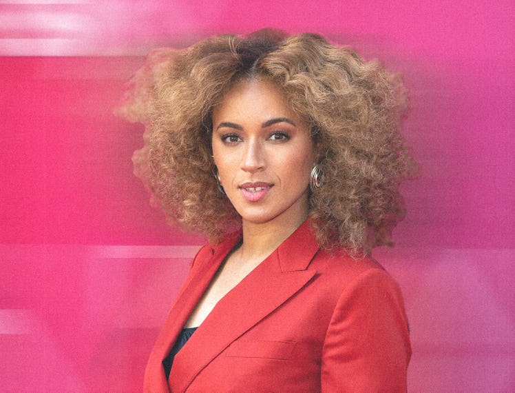 michelle de swarte wearing a red blazer against a blurred pink background