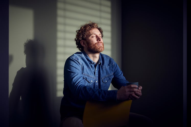 Middle-aged man sitting at desk with eyes closed in meditative pose