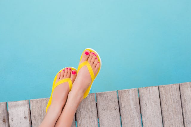 woman wearing yellow sandals with her feet by a pool