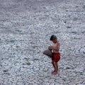 Child in barren drought-striken landscape in Asia 