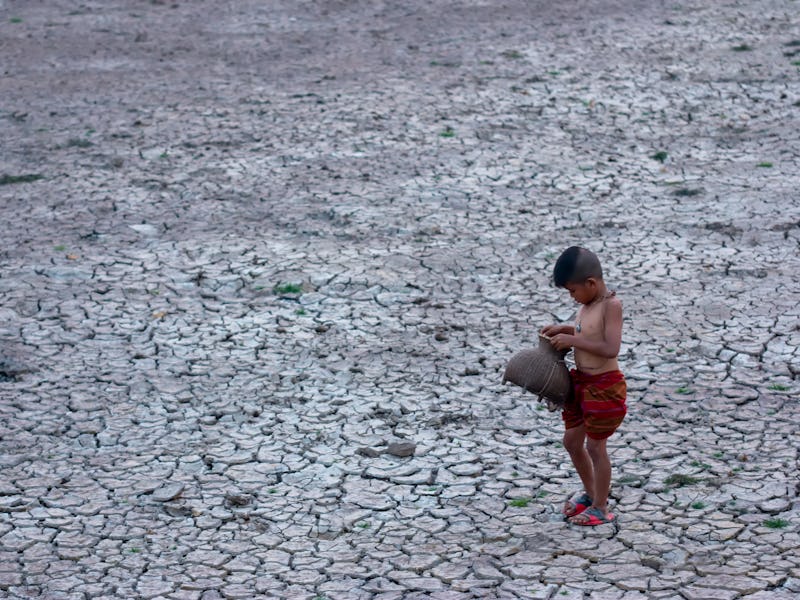 Child in barren drought-striken landscape in Asia