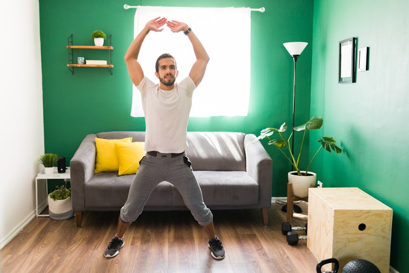 A man does jumping jacks during an at-home workout.