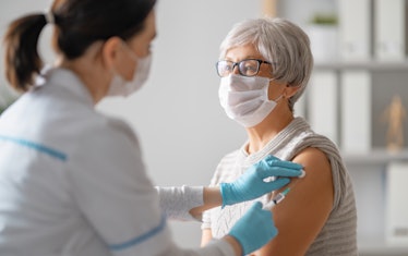 older woman in a mask getting a shot from a doctor
