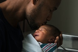 A Black man cradles his newborn son