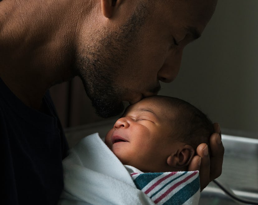 A Black man cradles his newborn son