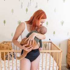 A mother wearing postpartum mesh panties while holding her baby