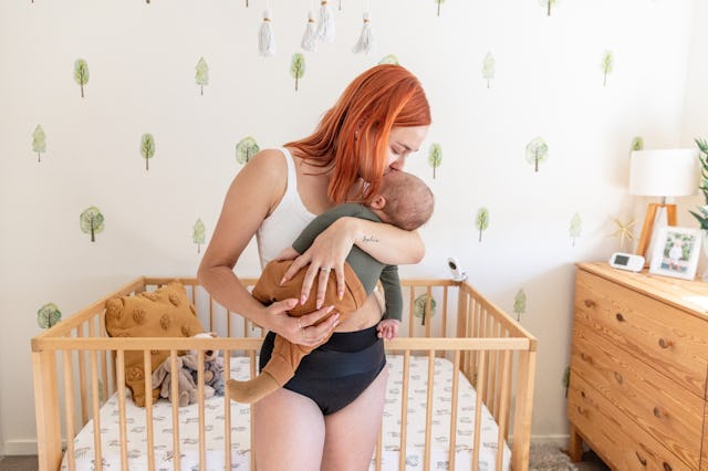 A mother wearing postpartum mesh panties while holding her baby