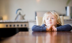 A child waits patiently at the dinner table.