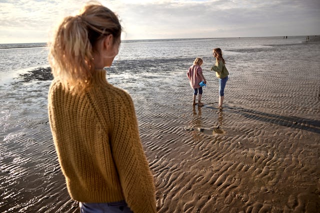 Mother watching her kids playing on the beach