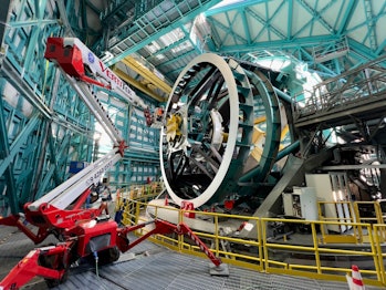 a crane near a large machine with a sky dome above it