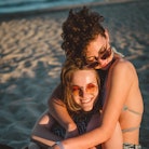 Young couple hugging on the beach during the 2022 summer solstice, which will affect every zodiac si...