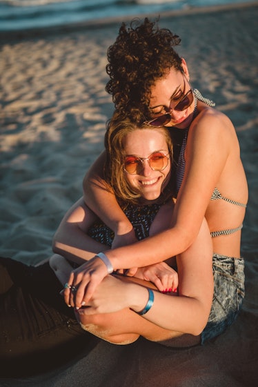 Young couple hugging on the beach during the 2022 summer solstice, which will affect every zodiac si...