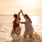 Young woman friends walking on the beach during the 2022 summer solstice, which has a beautiful spir...