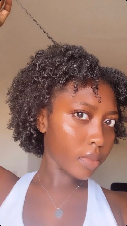 A woman with black curly natural hair pulling one of her locks