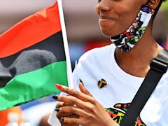 A woman celebrating the Juneteenth on a street with an African American flag