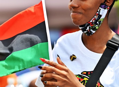 A woman celebrating the Juneteenth on a street with an African American flag
