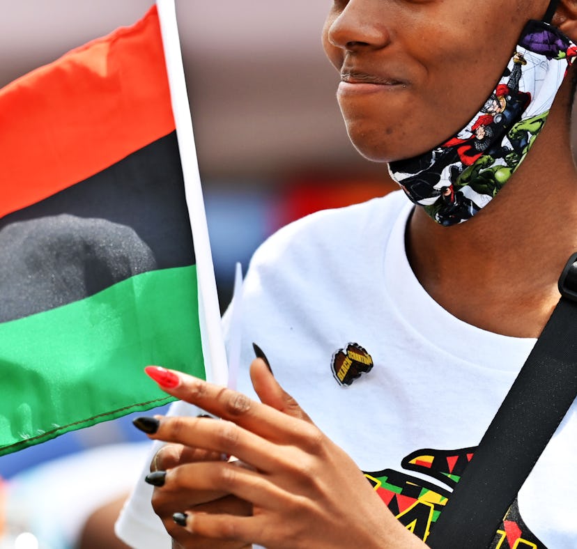 A woman celebrating the Juneteenth on a street with an African American flag