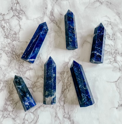Six sodalite crystal towers on a white marble background, a throat chakra crystal
