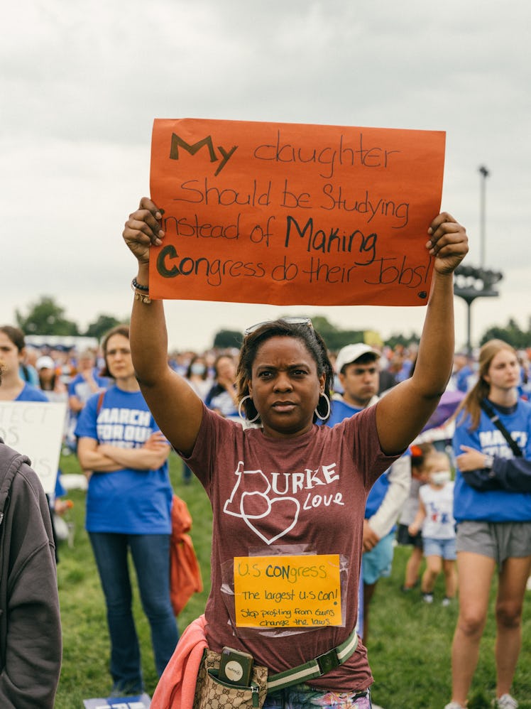 A protestor holding a homemade sign that reads, "My daughter should be studying instead of making co...