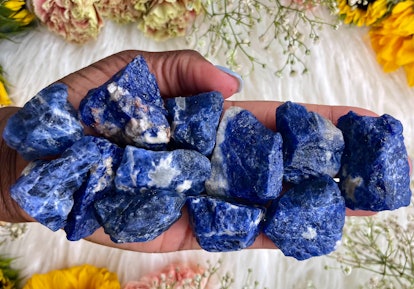 Close up of a palm full of raw lapis lazuli stones, a third-eye chakra crystal
