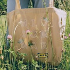 The BLOOMA bag from IKEA's BLOMMA collection is held in a meadow full of wildflowers.