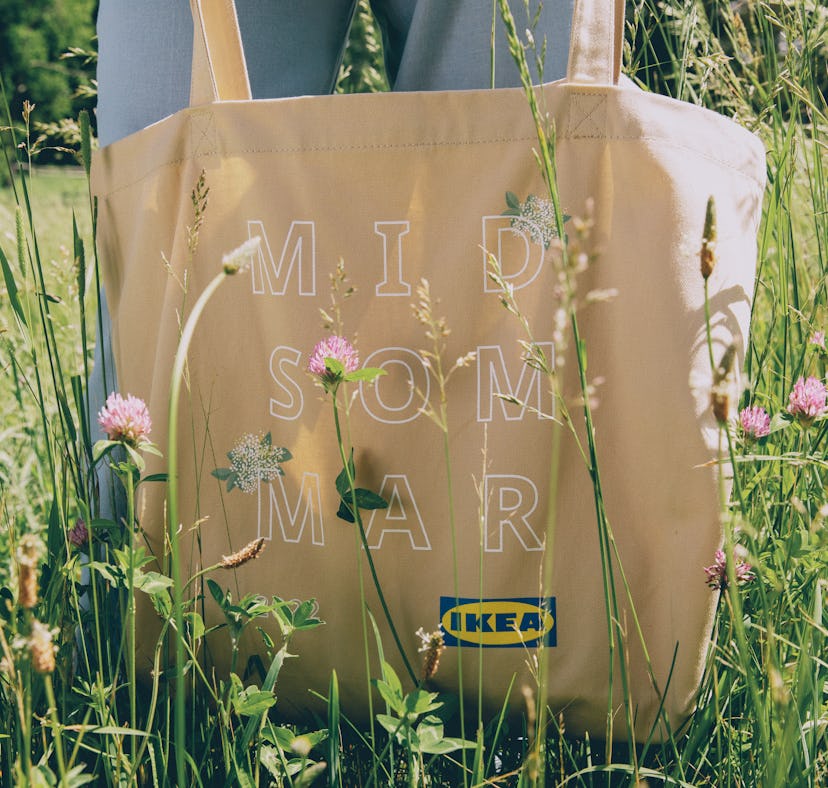 The BLOOMA bag from IKEA's BLOMMA collection is held in a meadow full of wildflowers.