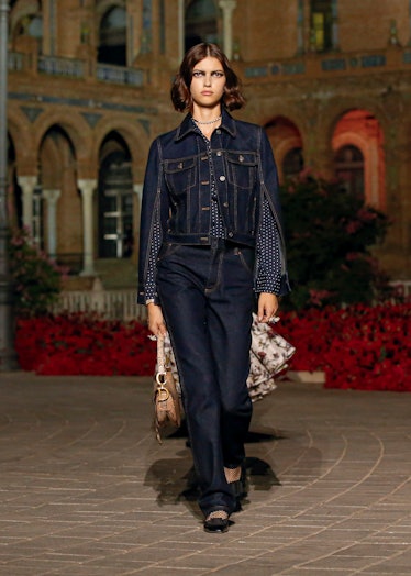 A female model walking in denim Dior pants and jacket