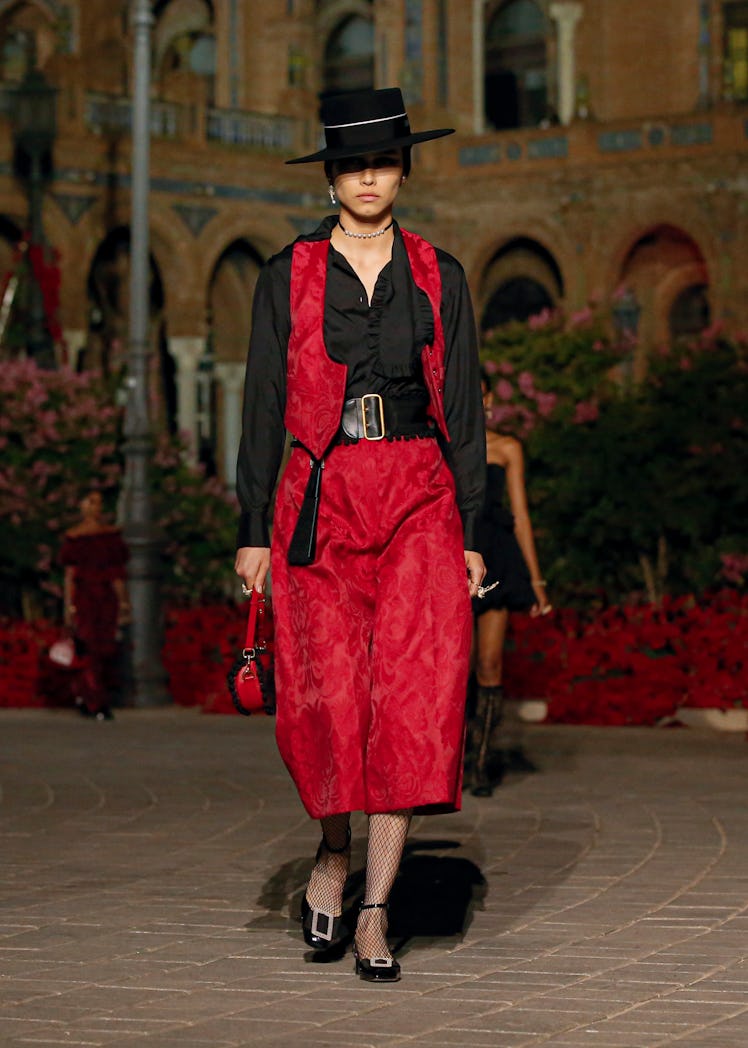 A model wearing red Dior pants and vest and a black shirt
