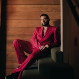 Johnny Sibilly lounging on the stairs, in a red suit