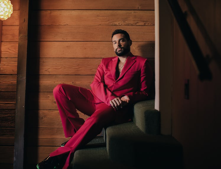 Johnny Sibilly lounging on the stairs, in a red suit