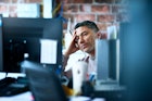 Man with hand on head at work looking tired and burnt out