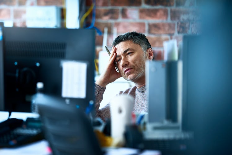 Man with hand on head at work looking tired and burnt out