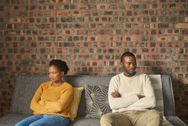 Black couple sitting on couch looking irritated at one another
