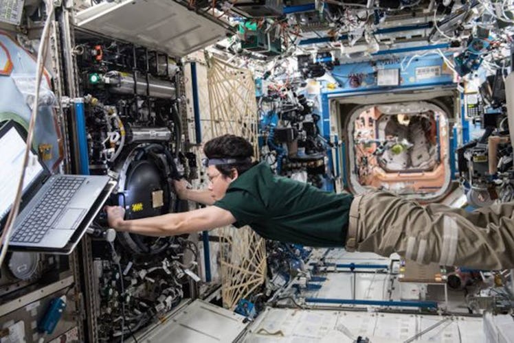 japanese astronaut floating in the ISS performing an experiment
