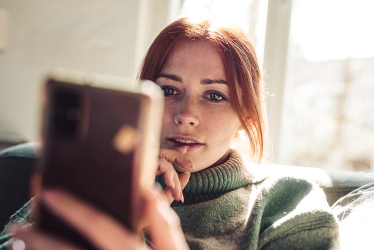 Woman with red hair reading text message