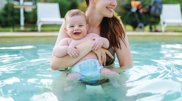 Best swim diapers - parent holding baby above the water in a pool