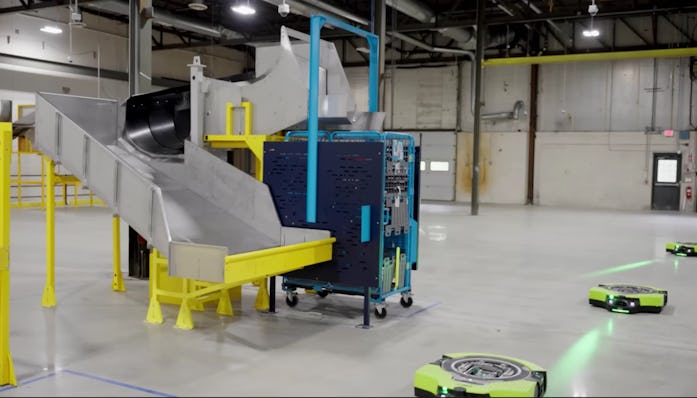 Three of Amazon's new autonomous Proteus warehouse robots traveling through warehouse in a straight ...