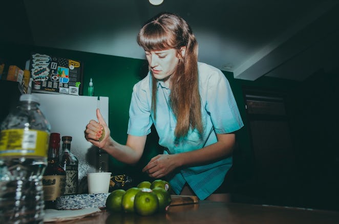 Los Bitchos member Nic Crawshaw, wearing a blue T-shirt, is preparing lime juice for margaritas