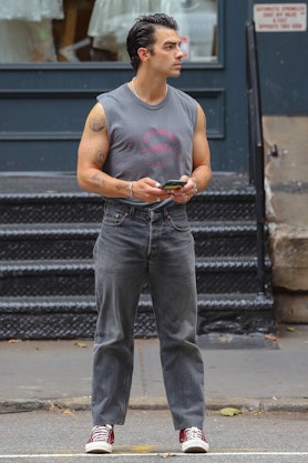 Joe Jonas standing in a grey sleeveless shirt