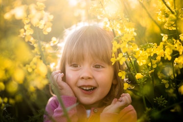 A girl surrounded by spring flowers laughing.