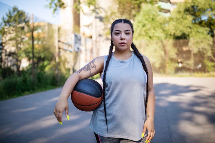 Young woman holding a basketball in July 2022, the worst month per her zodiac sign's horoscope.