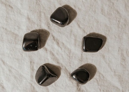 Five shungite stones, a crystal for empaths, in a circle on a cloth